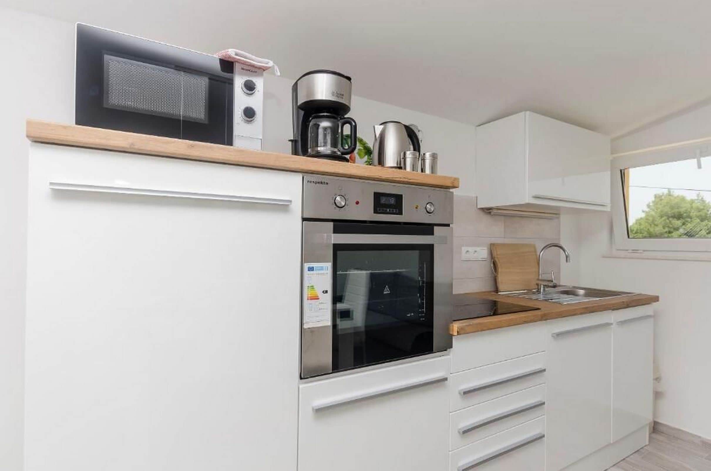 A compact kitchen with a built-in oven, microwave, and coffee maker.