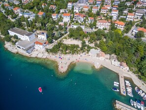 An aerial view of a coastal area with a beach, a marina with boats, and residential buildings. - Apartment Kristina (Crikvenica)