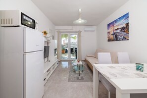 A compact kitchen with a refrigerator, microwave, and a glass coffee table. - Apartments Grozdana (Crikvenica)