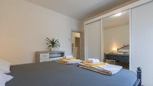 A bedroom with a bed, a bedside table with a plant, and a mirror reflecting a staircase. - Apartment Zeljka (Crikvenica)