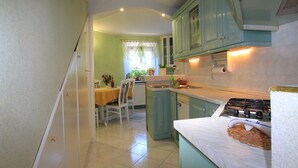 Una cocina con armarios color turquesa, una encimera blanca y un comedor con mesa y sillas.