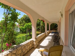 A covered outdoor area with stone walls, a table, and chairs. - Apartments Vanessa (Crikvenica)