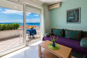 A balcony with a view of the sea, a sofa with colorful cushions, and a table with a vase of flowers. - Apartments Vanessa (Crikvenica)