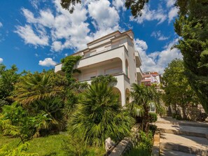 A multi-story building with balconies, surrounded by lush greenery and palm trees. - Apartments Vanessa (Crikvenica)