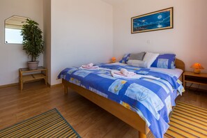 A bedroom with a bed, a potted plant, a night lamp, and a painting on the wall. - Apartments Vanessa (Crikvenica)