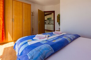 A bedroom with a bed, a wardrobe, and a view into the kitchen. - Apartments Vanessa (Crikvenica)
