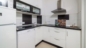 Una cucina moderna con mobili bianchi, un piano di lavoro nero, un forno a microonde, una lavastoviglie e una cappa aspirante in acciaio inossidabile.