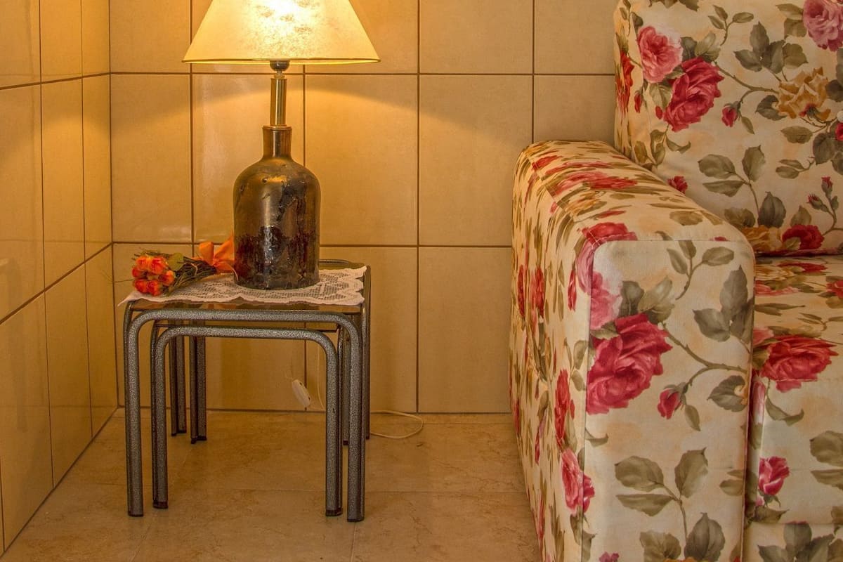 Una stanza con un letto, un tavolo con una lampada e un'opera d'arte incorniciata al muro.