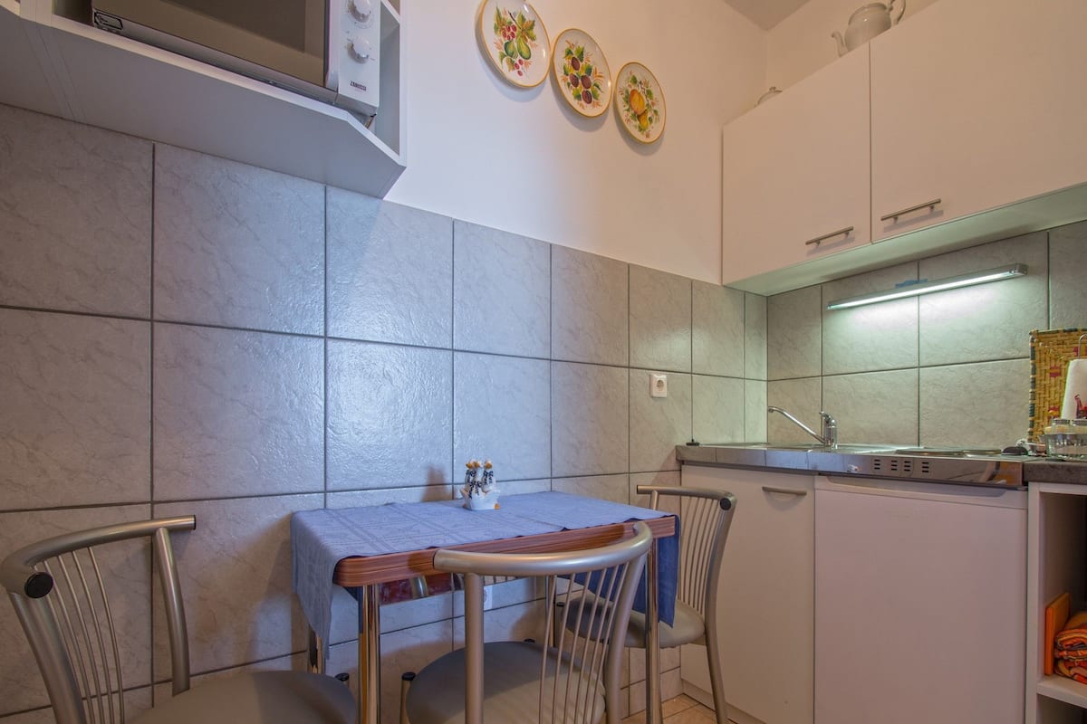 Una cucina compatta con un tavolo e sedie, forno integrato e un piccolo lavandino.