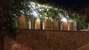 A stone wall with wooden shutters and a string of lights. - Apartment Milivoj (Primosten)