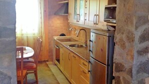 A kitchen with stone archway, wooden cabinets, stainless steel appliances, and a dining area with a table and chairs. - Apartment Milivoj (Primosten)