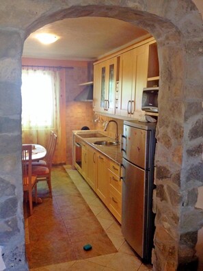 Una cocina con arco de piedra, armarios de madera, electrodomésticos de acero inoxidable y una zona de comedor con mesa y sillas.