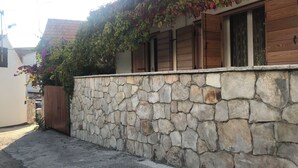 A stone wall with a wooden fence and a building with windows. - Apartment Milivoj (Primosten)