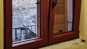A wooden-framed window with a view of a construction site. - Apartment Milivoj (Primosten)