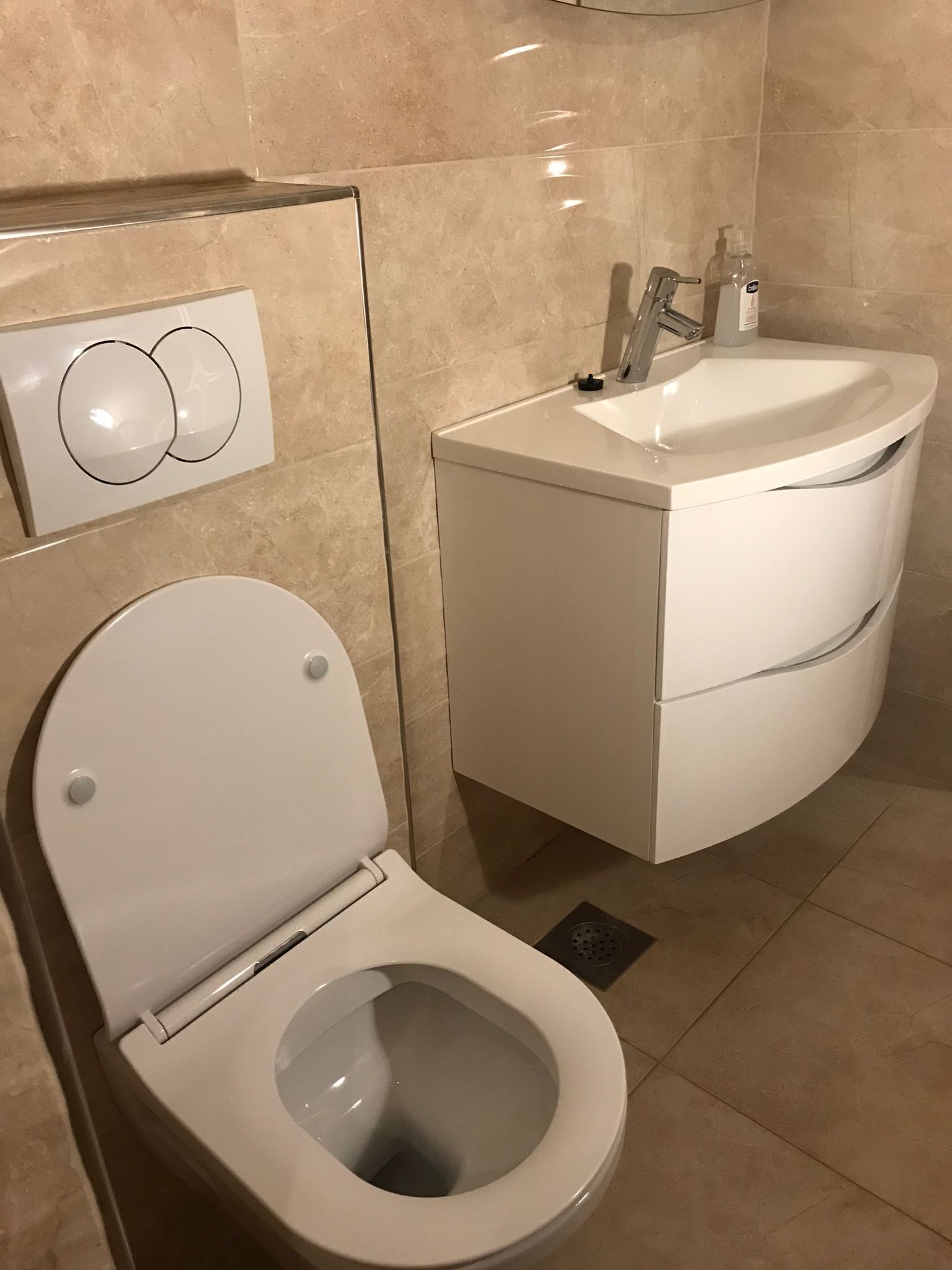 Moderni kylpyhuone, jossa on wc, pesuallas ja seinälle asennettu ohjauspaneeli.
