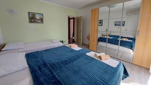 Une chambre avec deux lits, un grand miroir et un tableau au mur.