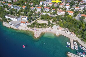 An aerial view of a coastal area with a beach, boats, and residential buildings. - Apartments Novoselic (Crikvenica)
