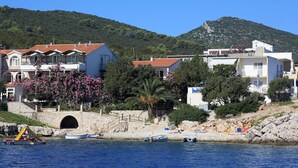 A coastal town with stone buildings, a clear blue sky, and a mountain in the background. - Apartment Martina (Jelsa)
