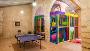 A room with a ping pong table, stone walls, and a colorful play area. - Agrotourism "Es Rafalet - Casa Amitger" countryside views, pool, Wi-Fi, A/C, and garden (Manacor)