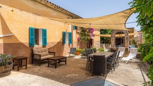 An outdoor patio with furniture, a shaded area, and a building with blue shutters. - Agrotourism "Es Rafalet - Casa Amitger" countryside views, pool, Wi-Fi, A/C, and garden (Manacor)