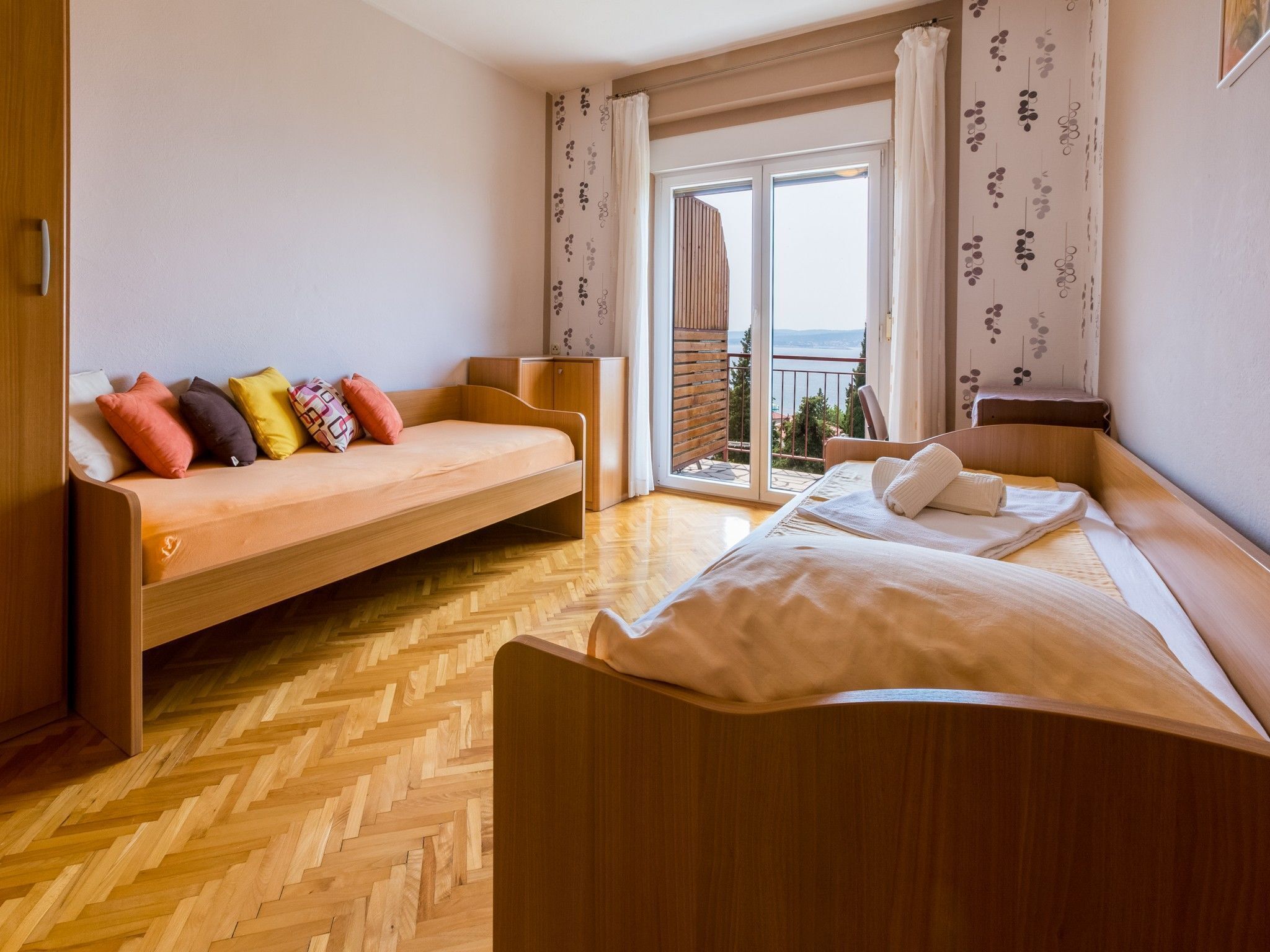 A room with a bed, a sofa, and a balcony with a view.