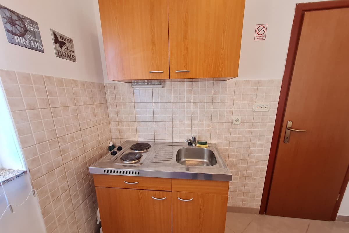 Une cuisine de taille réduite, dotée de meubles en bois, d’un évier en acier inoxydable et d’une cuisinière à gaz.