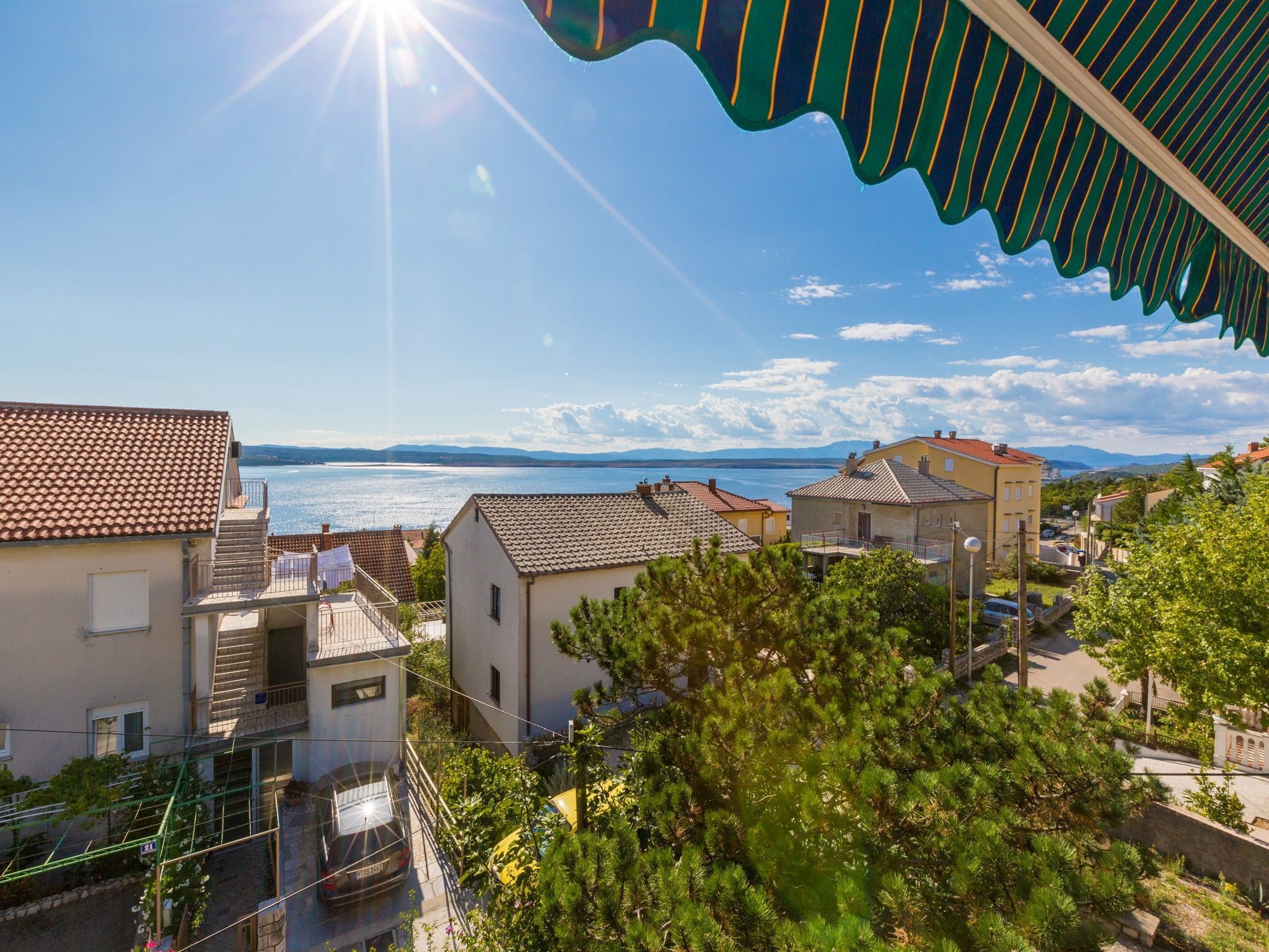 A residential area with houses, a clear sky, and a view of the sea.