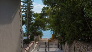 A coastal pathway leading to a beach with a stone wall on one side and a building on the other. - Apartment Villa Sara (Crikvenica)