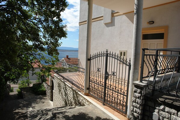 A balcony with a wrought iron gate, a stone wall, and a view of the sea. - Apartments Badnje (Crikvenica)