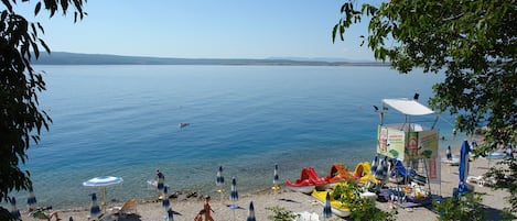 A beach with umbrellas, lounge chairs, and a lifeguard tower.