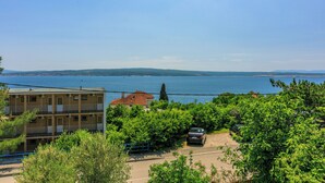 Un quartier résidentiel en bord de mer, avec un immeuble à plusieurs étages, une voiture garée et une vue sur la mer.