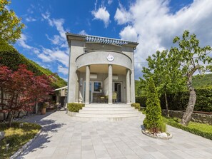 A building with a circular entrance, a clock on the facade, and a paved walkway leading to it. - Apartments and Room Rabbit (Crikvenica)