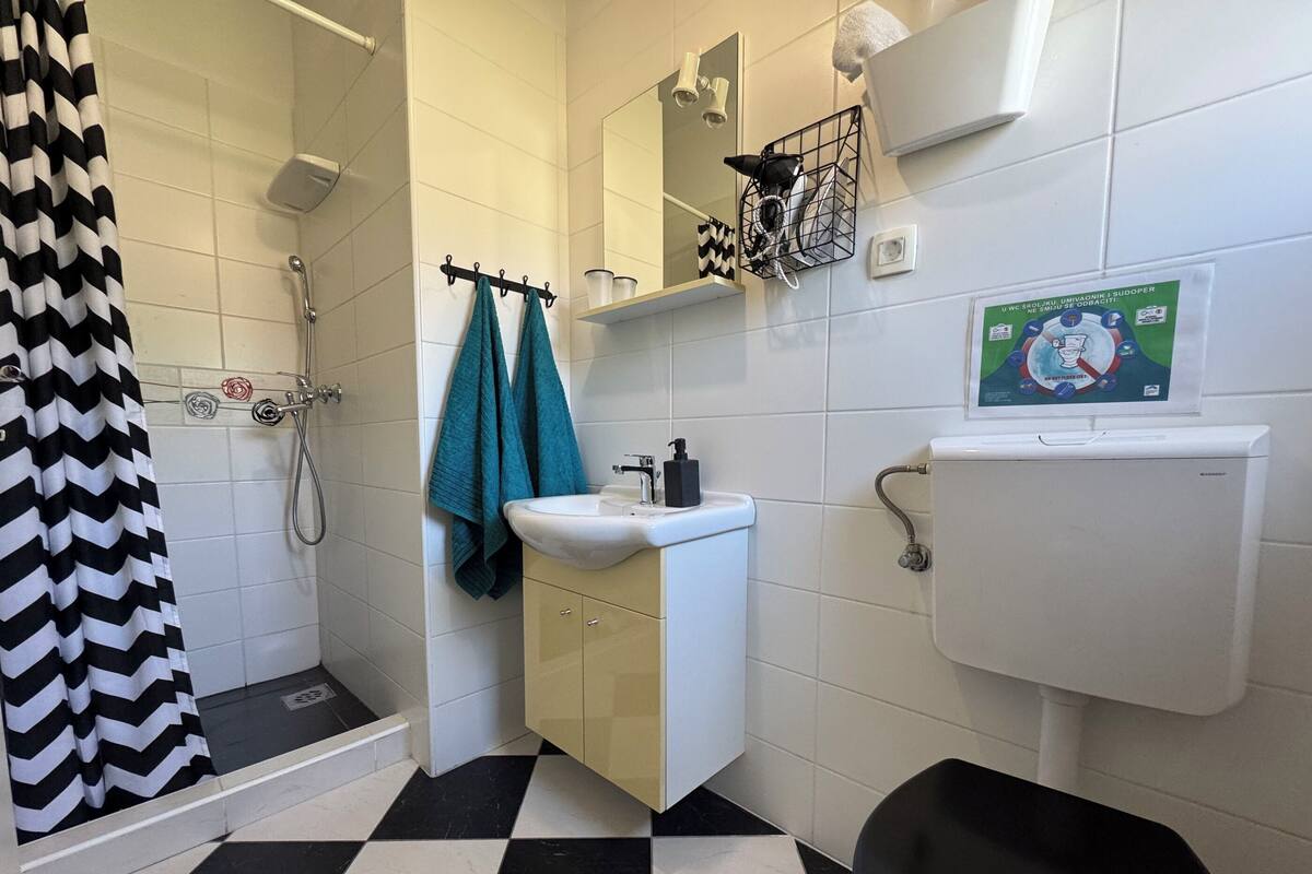 A bathroom with a shower, sink, toilet, and a mirror.