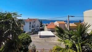 Zona residenziale con vista libera sul mare, caratterizzata da edifici con tetti in tegole rosse e un edificio bianco con un balcone.