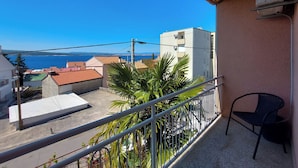 Un balcone con vista sul mare, una sedia e un edificio con tetto in tegole.