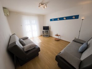 A living room with two sofas, a TV stand, and a small table. - Apartments Cacija (Okrug)