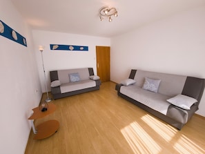 A modern living room with two sofas, a floor lamp, and a small wooden table. - Apartments Cacija (Okrug)