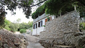Un edificio de paredes de piedra con un estrecho sendero que lleva a una puerta de madera.
