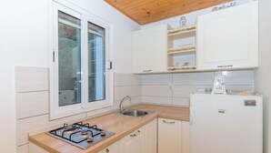 Una cocina compacta con estufa a gas, un lavamanos y un refrigerador.