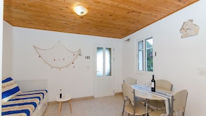 Una habitación con una cama, una mesa con sillas, un adorno de red colgante y una puerta con paneles de vidrio esmerilado.