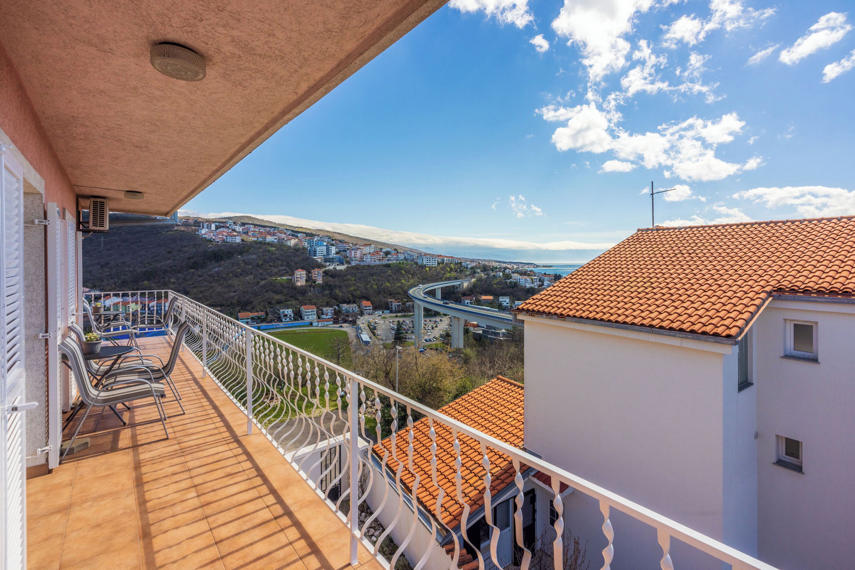 Ein Balkon mit Blick auf eine Küstenstadt, eine Brücke und eine hügelige Landschaft.