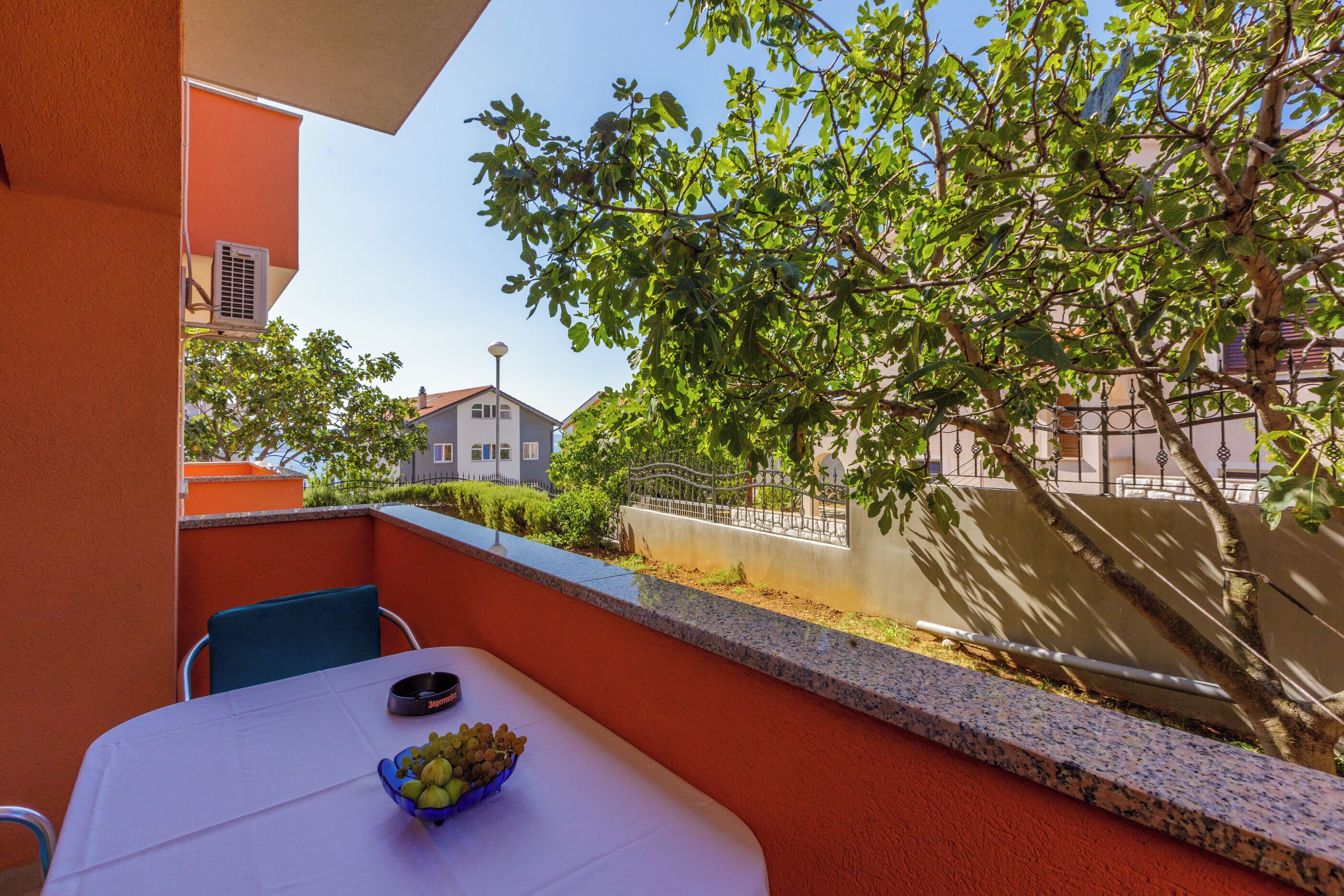 A balcony with a table, chairs, and a bowl of fruit.