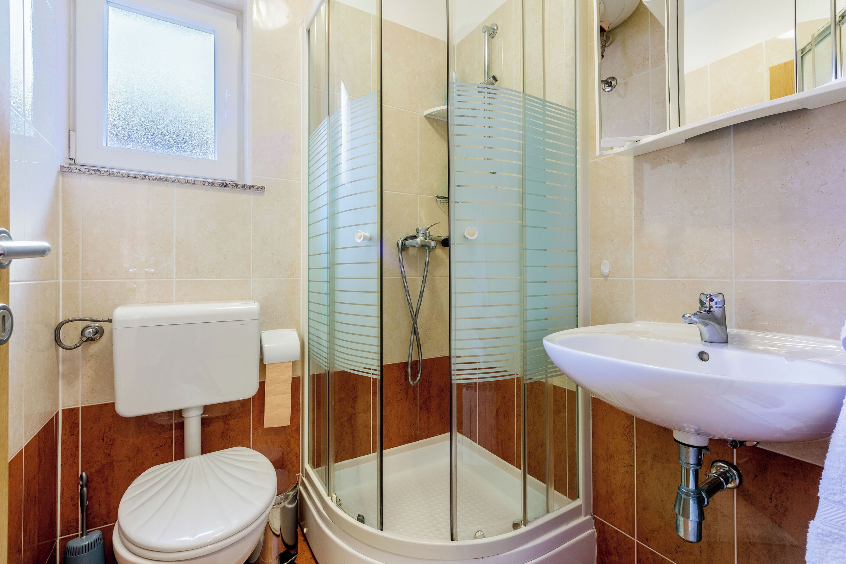Ein Badezimmer mit Duschkabine, Toilette und Waschbecken.