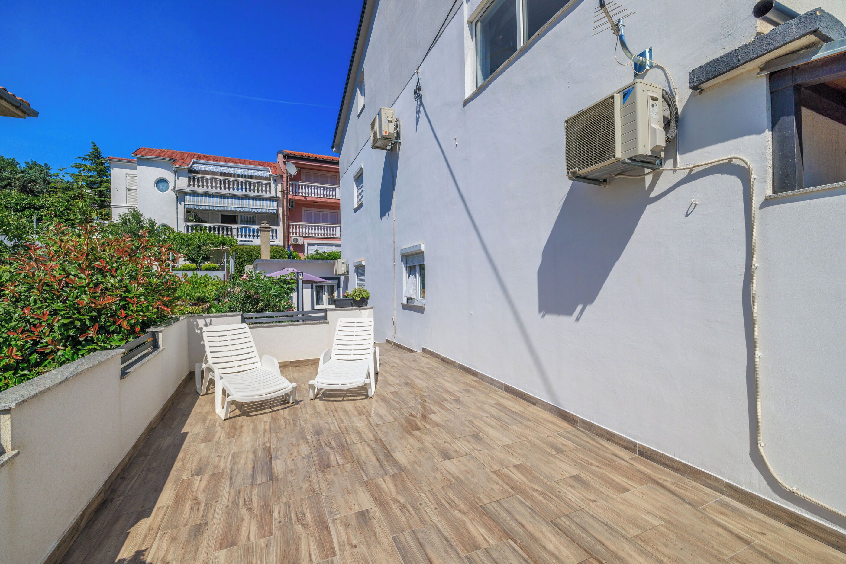Una terraza en la azotea con dos sillones blancos, una mesita y una planta en maceta.
