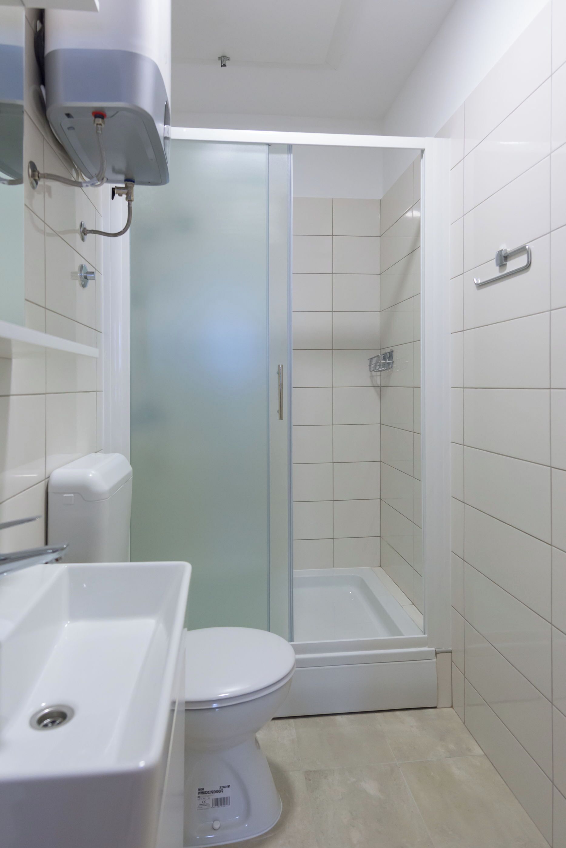 Een badkamer met toilet, wastafel en een douchecabine met glazen wanden.