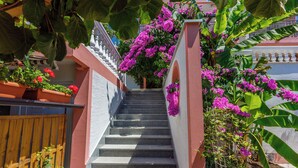 A staircase with a railing, surrounded by potted plants and flowering vines. - Apartments Marijana (Crikvenica)