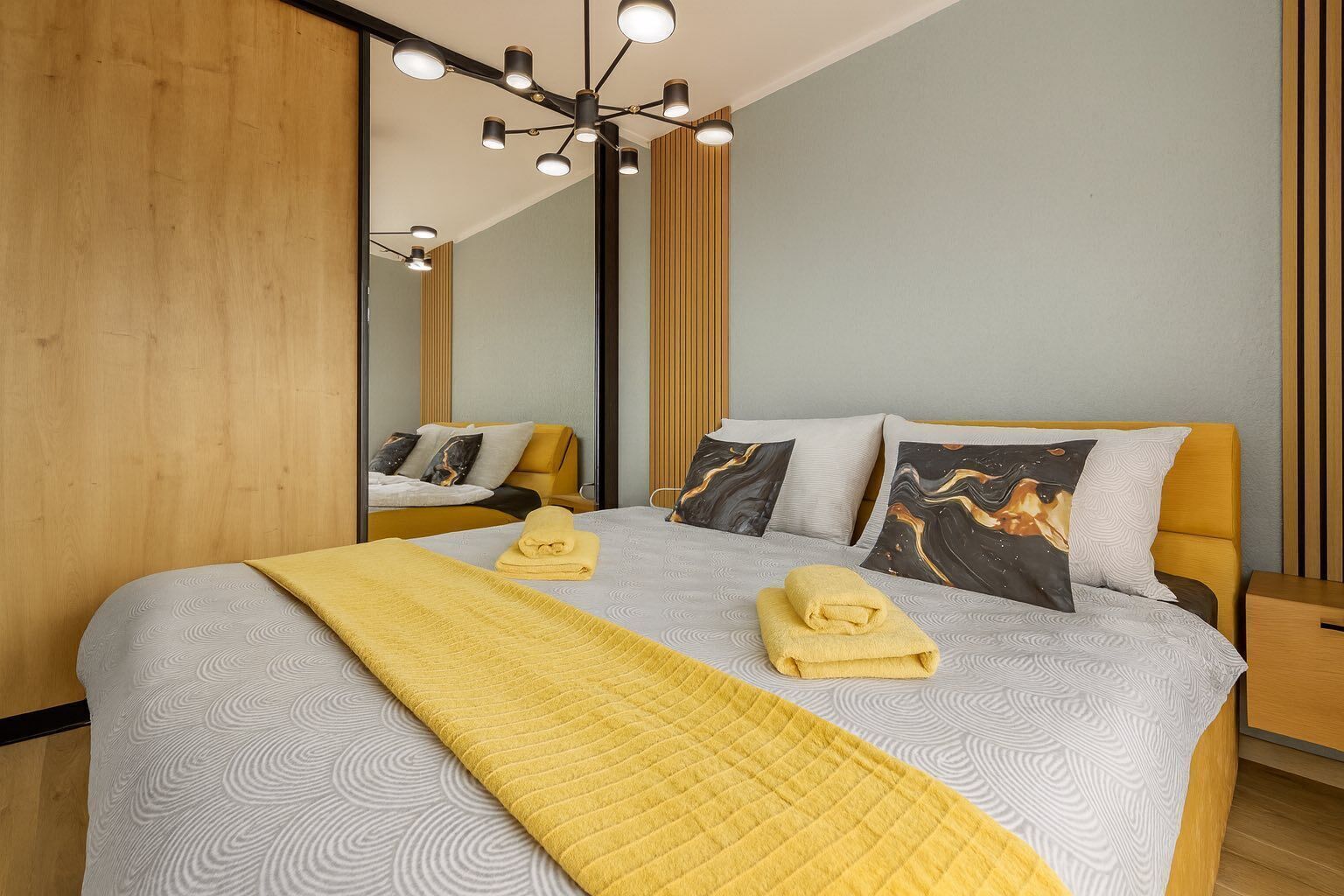 Een moderne hotelkamer met een groot bed, een spiegel en een bijzondere plafondlamp.