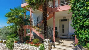 A two-story building with a stone wall, a staircase, and a balcony. - Apartments Marijana (Crikvenica)