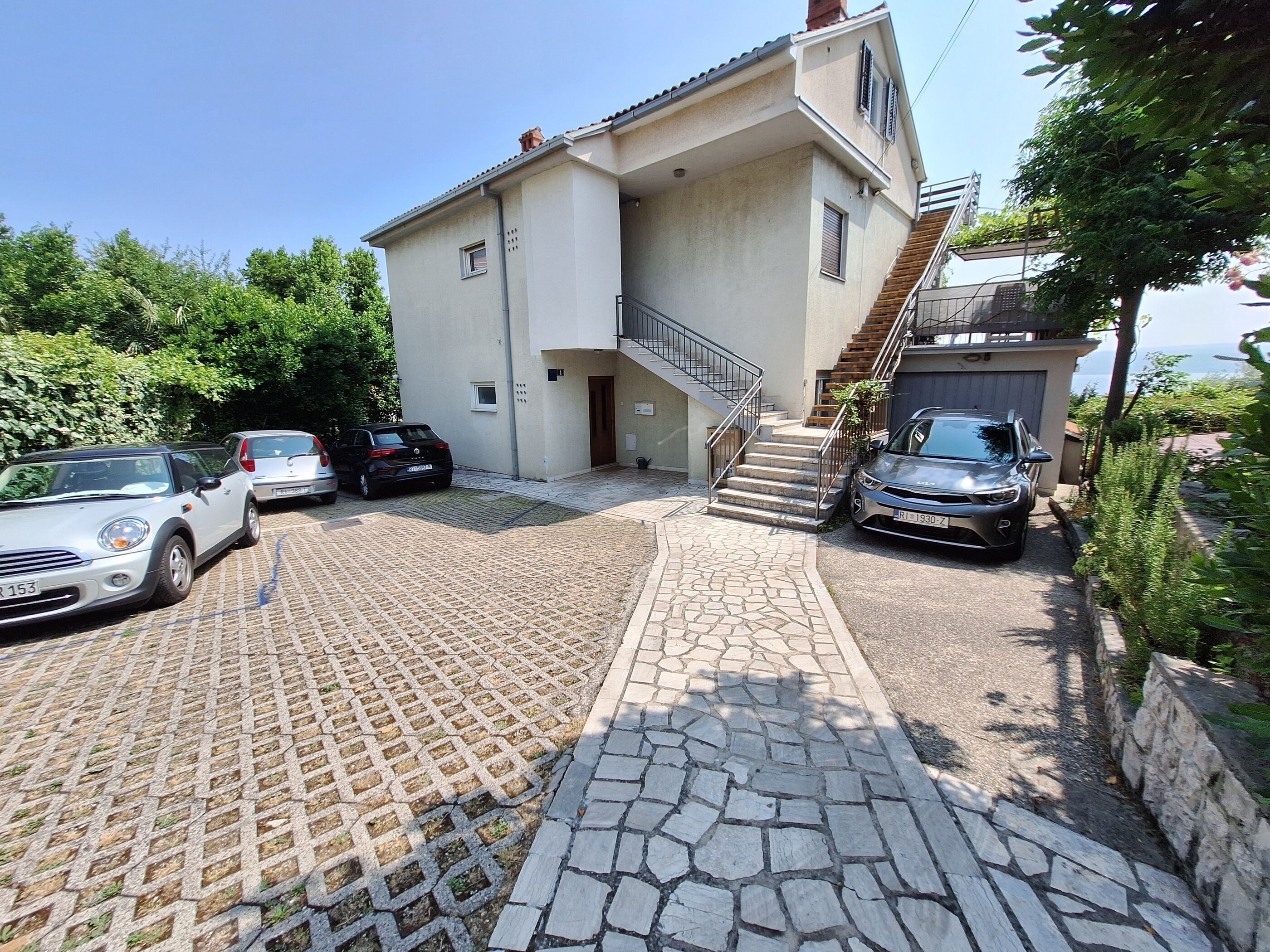 A two-story building with a stone-paved driveway and a staircase leading to the upper floor.