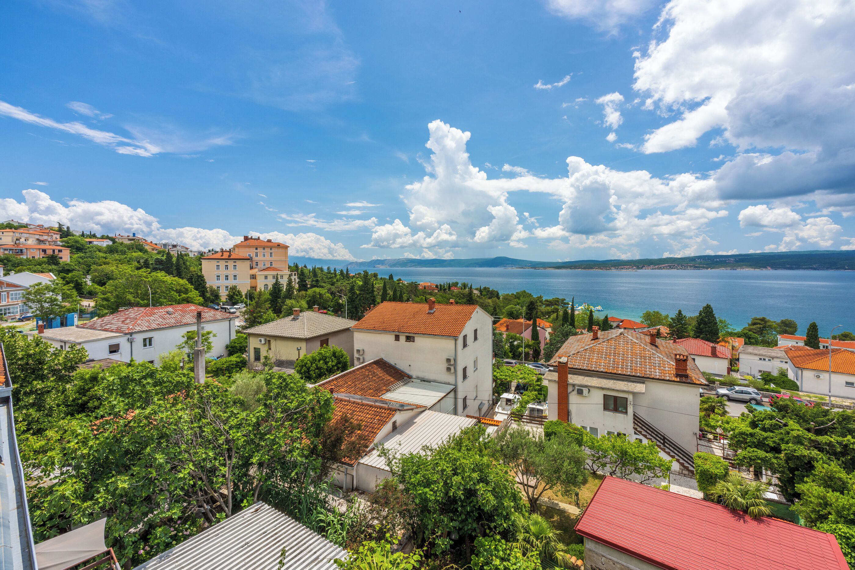 A coastal town with buildings, trees, and a view of the sea.
